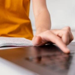 pessoa-escrevendo-em-um-caderno-e-utilizando-o-computador